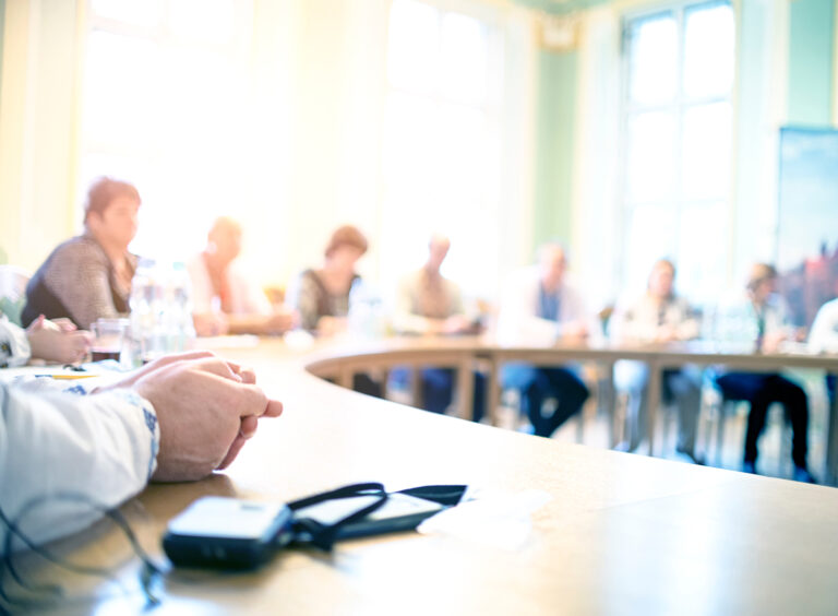 stock-photo-people-at-a-round-table-discuss-different-issues-focus-on-hand-1113593240